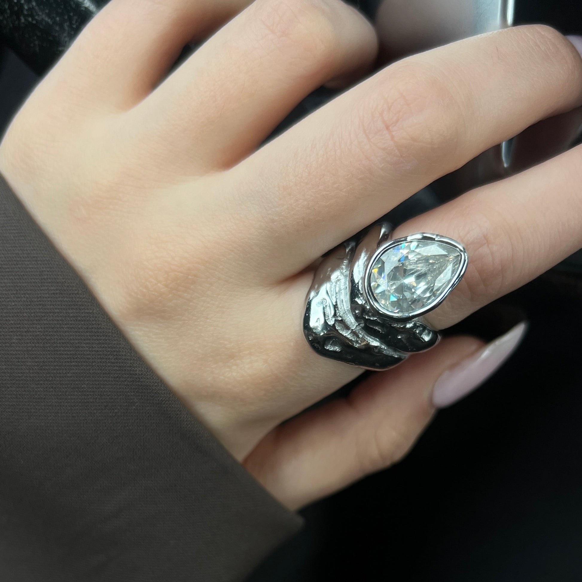 תקריב של טבעת Sol במראה מתכת נוזלית עם אבן שקופה.